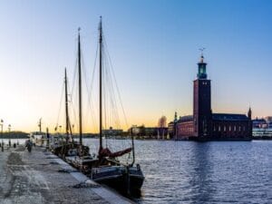 Stunning view of Stockholm City Hall with sailing boats at sunset.